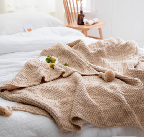 Strikket pledd med dusker i sofaen